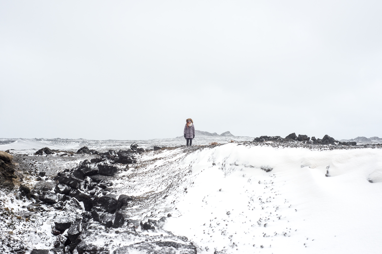Island im Winter Mädchen mit jacke und Pelz steht im Wind
